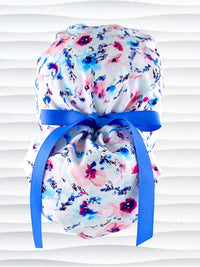 Ponytail style surgical scrub cap with abstract flowers in pinks and blues all over white premium cotton fabric and finished with grosgrain ribbon ties.