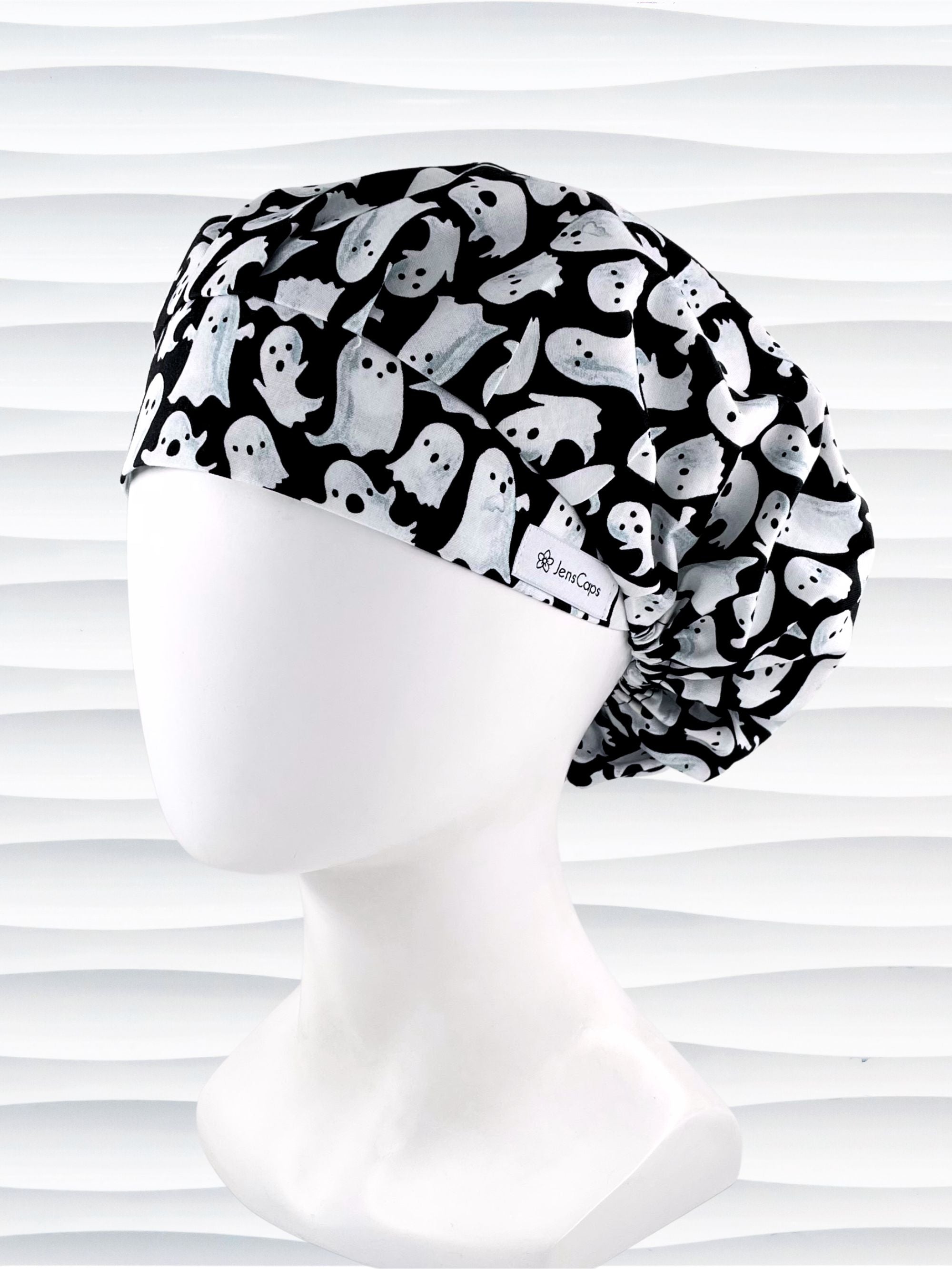 Bouffant style surgical scrub cap with white animated ghosts all over this black cotton fabric.