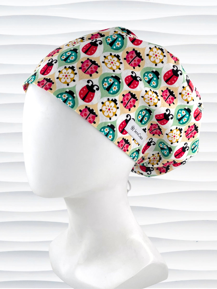 Euro Pixie style surgical scrub cap by JenCaps has ladybugs and flowers in a retro theme on cotton fabric and finished with a grosgrain ribbon.