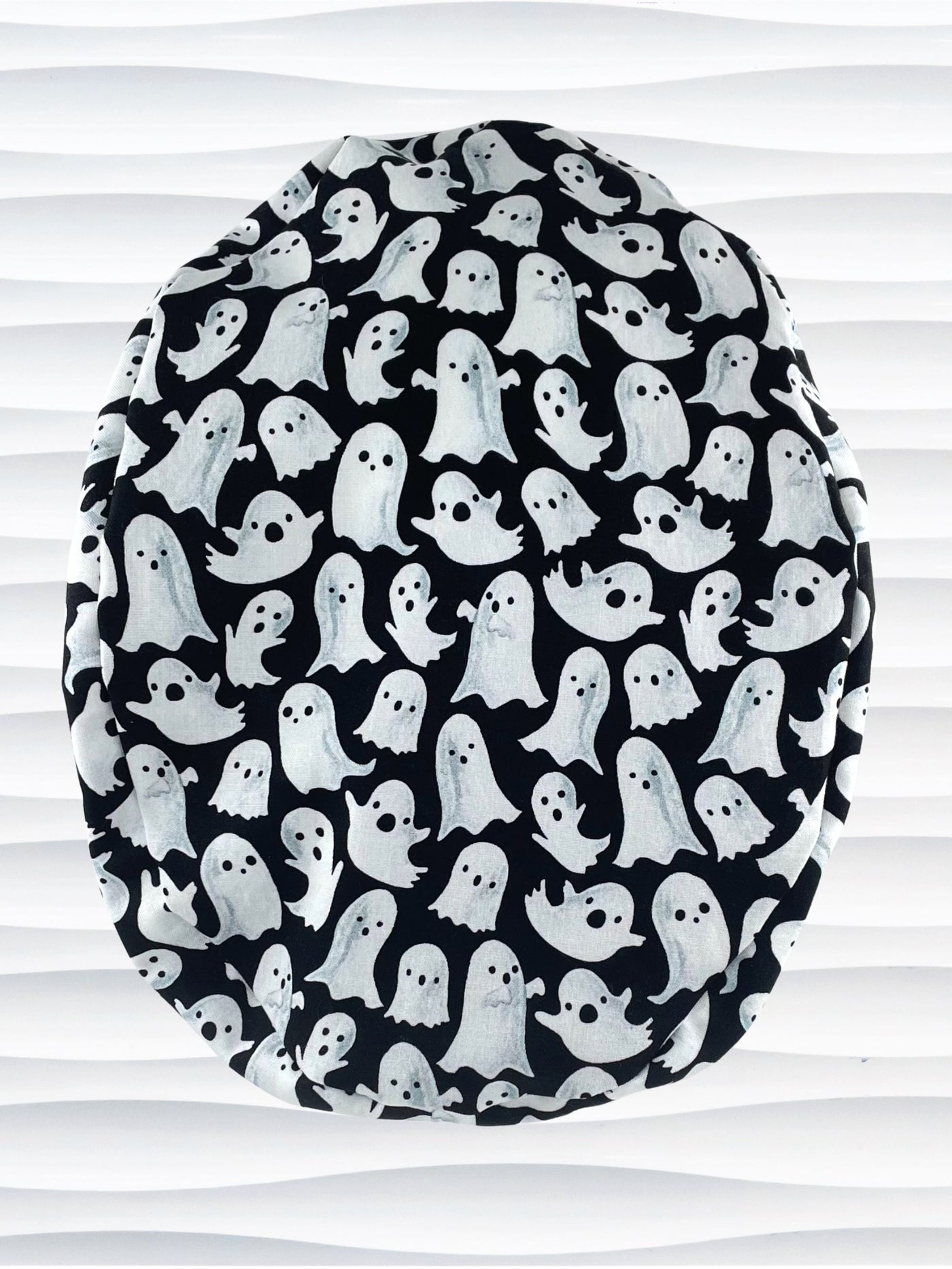 Euro Pony style surgical ponytail scrub cap with friendly white ghosts tossed all over black cotton fabric and finished with grosgrain ribbon ties.