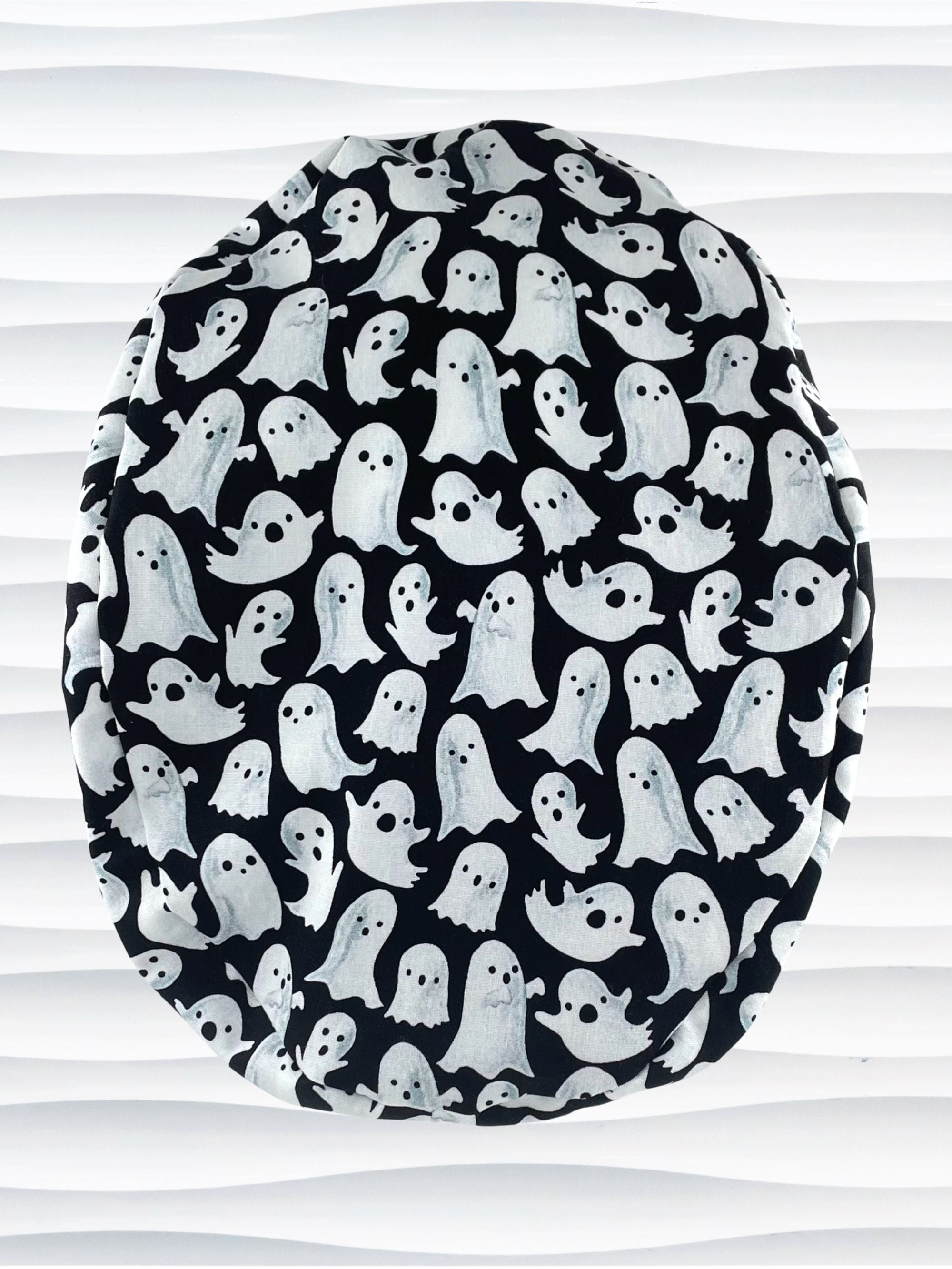 Euro Pony style surgical ponytail scrub cap with friendly white ghosts tossed all over black cotton fabric and finished with grosgrain ribbon ties.