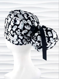 Euro Pony style surgical ponytail scrub cap with friendly white ghosts tossed all over black cotton fabric and finished with grosgrain ribbon ties.
