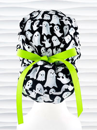 Euro Pony style surgical ponytail scrub cap with friendly white ghosts tossed all over black cotton fabric and finished with grosgrain ribbon ties.