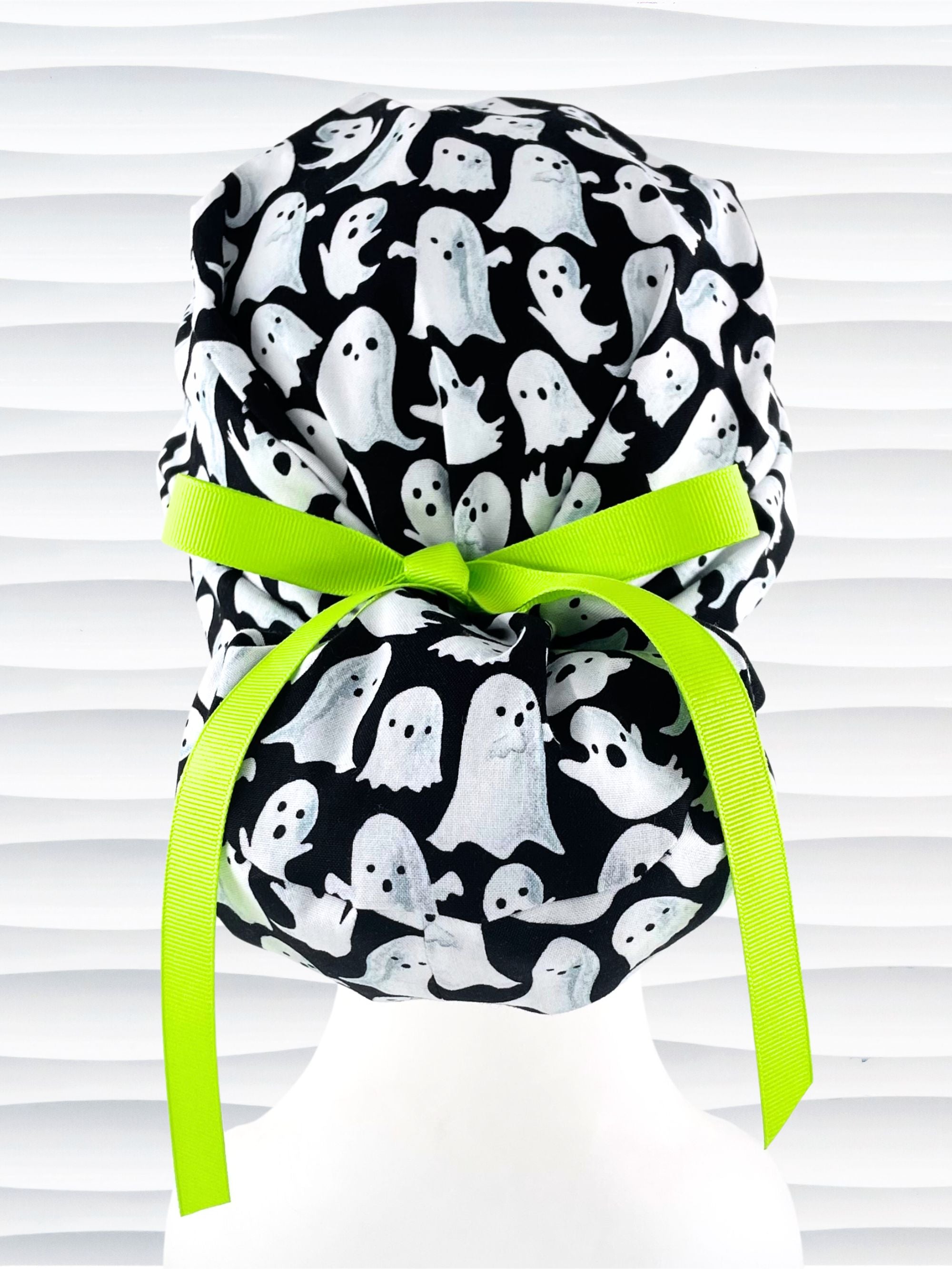 Euro Pony style surgical ponytail scrub cap with friendly white ghosts tossed all over black cotton fabric and finished with grosgrain ribbon ties.