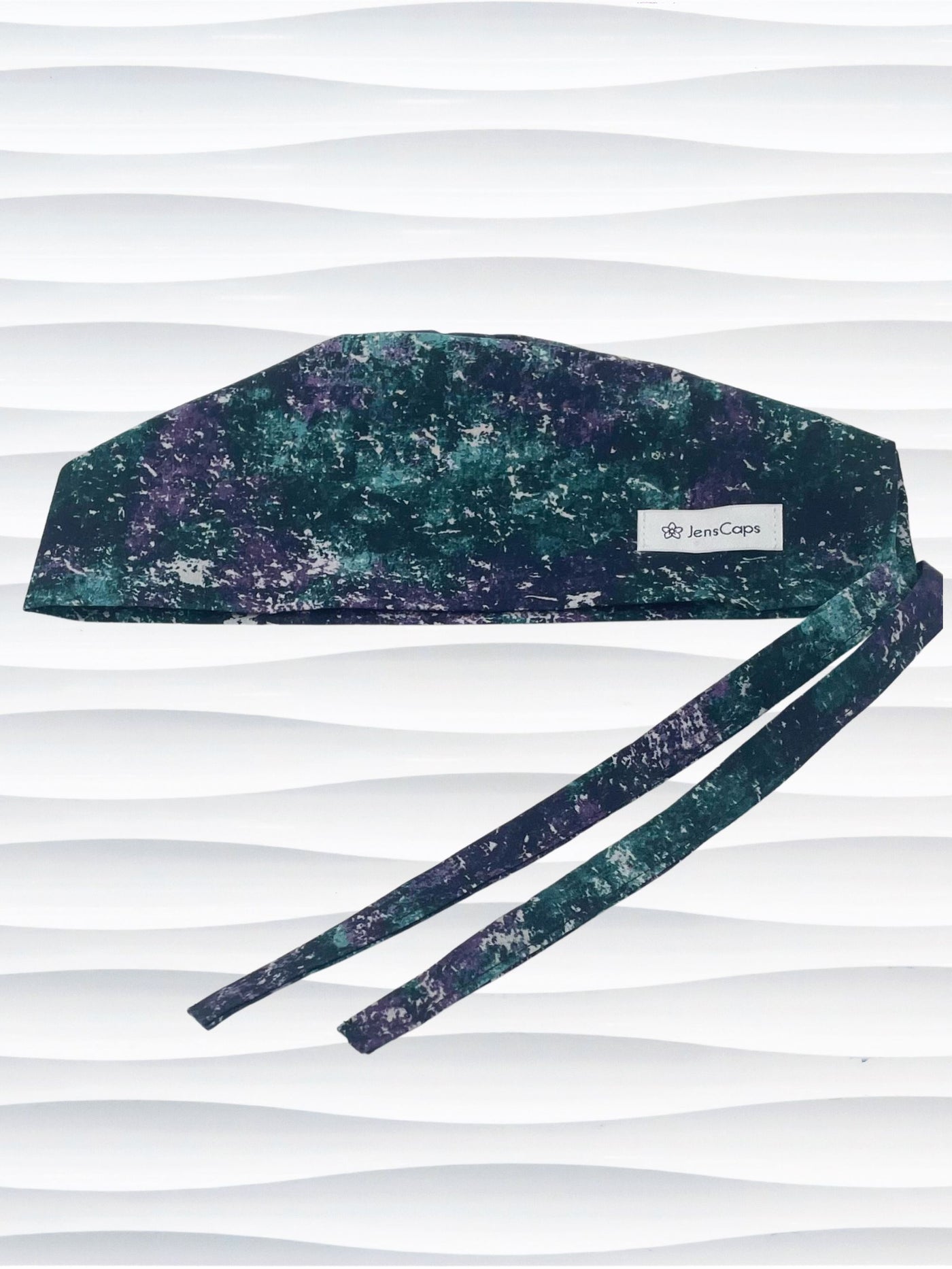 Surgeon style surgical scrub cap with an abstract print in teal, gray, and deep purples on cotton fabric.