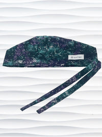 Surgeon style surgical scrub cap with an abstract print in teal, gray, and deep purples on cotton fabric.