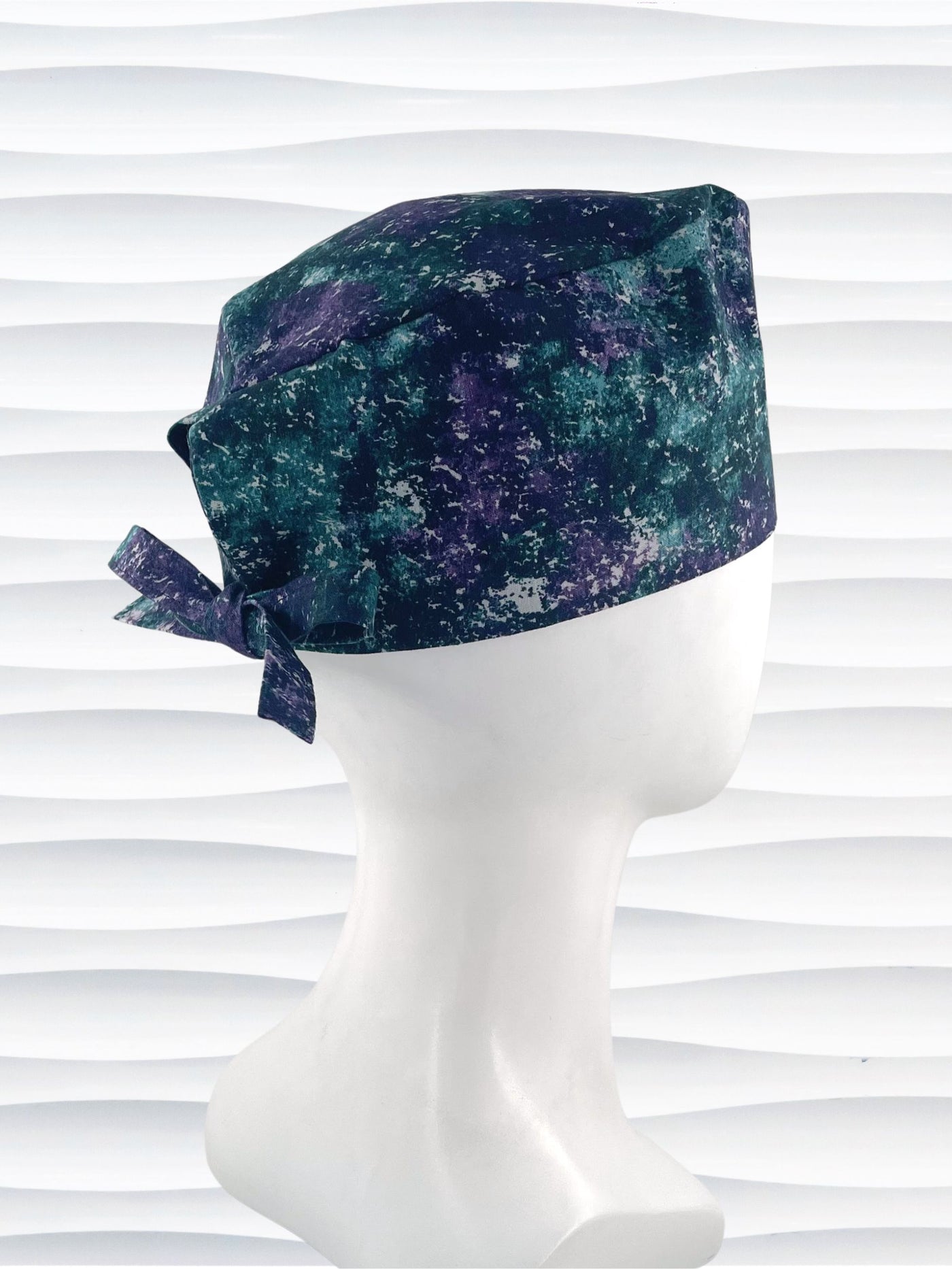 Surgeon style surgical scrub cap with an abstract print in teal, gray, and deep purples on cotton fabric.