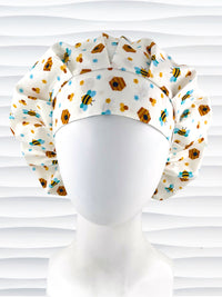 Bouffant style surgical scrub cap with an allover print of bumble bees, beehives, honeycombs, and flowers on white cotton fabric 