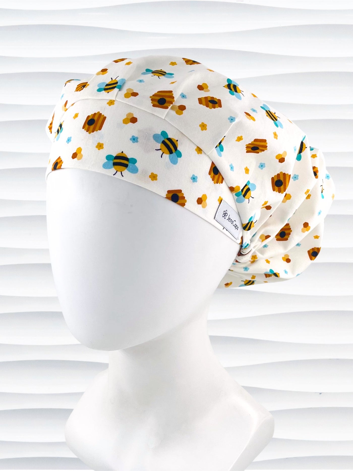 Bouffant style surgical scrub cap with an allover print of bumble bees, beehives, honeycombs, and flowers on white cotton fabric 