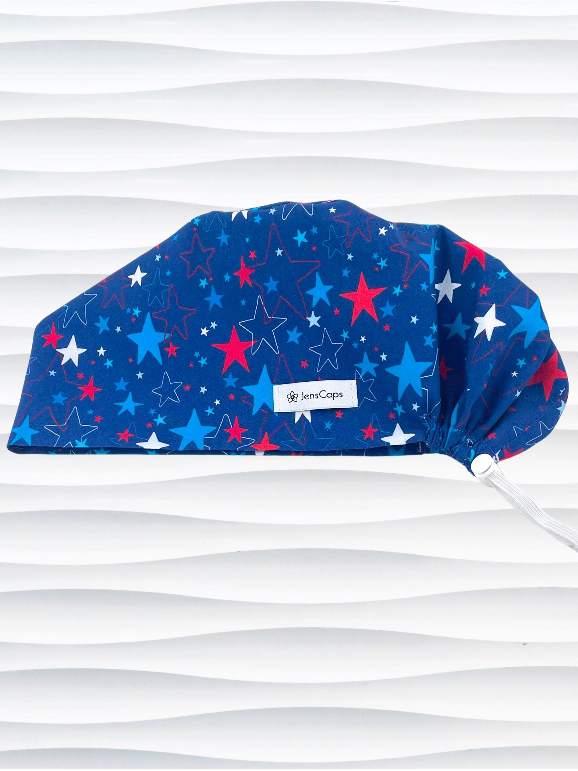 Euro Pixie style surgical scrub cap with an allover print of country style red white and blue stars on royal blue cotton fabric.