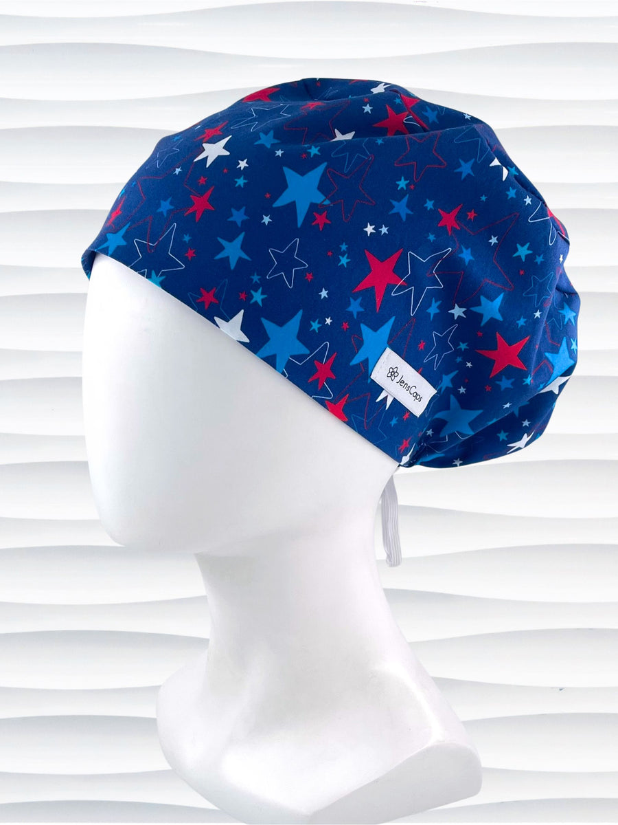 Euro Pixie style surgical scrub cap with an allover print of country style red white and blue stars on royal blue cotton fabric.