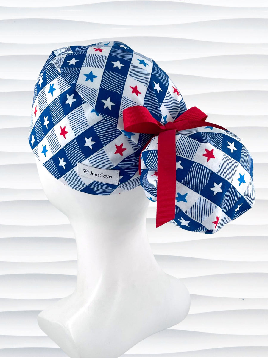 Ponytail pouch style surgical scrub cap with a fun plaid print in blue and white with red, white, and blue stars on cotton fabric.