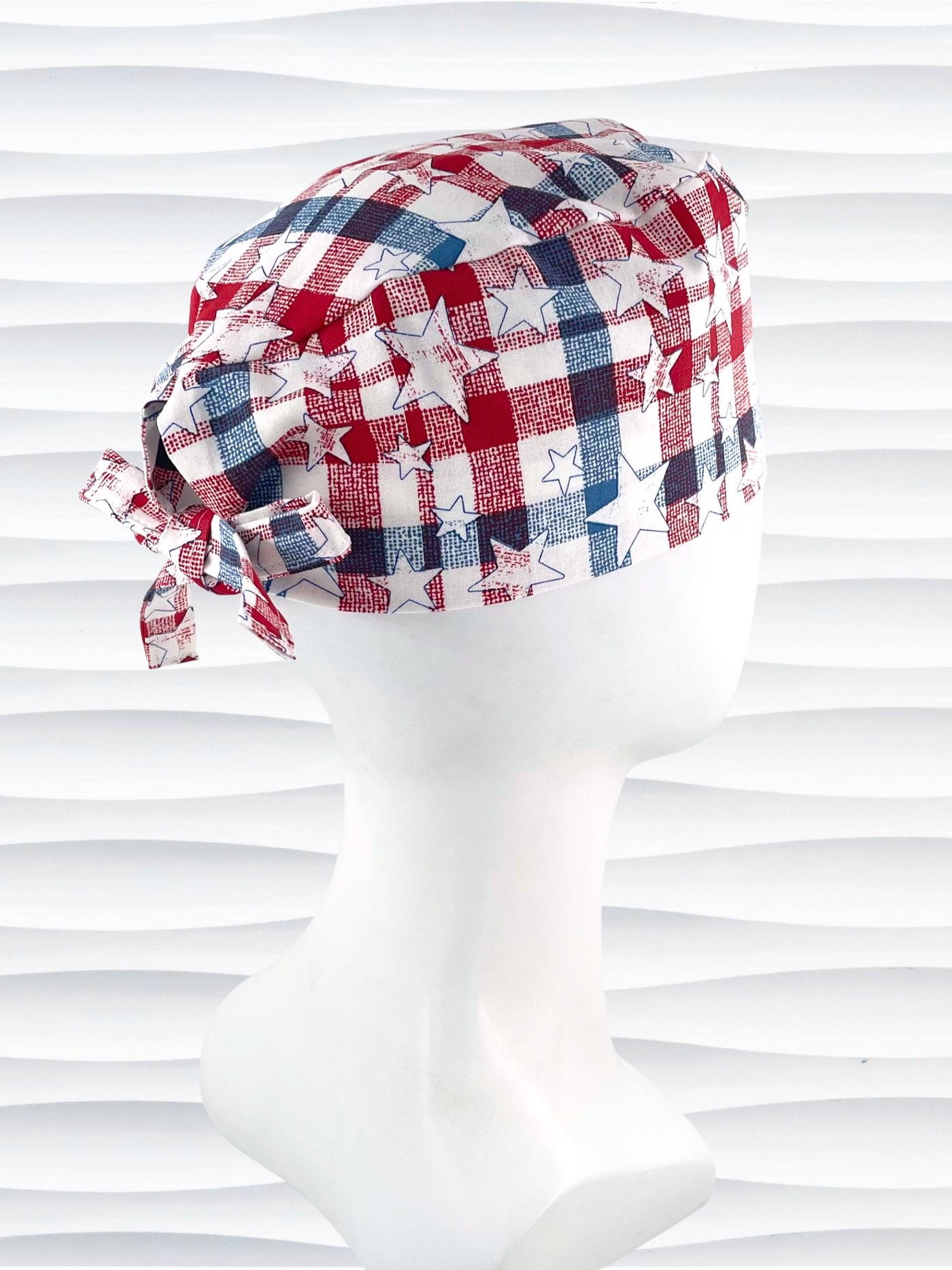 Surgeon style surgical scrub cap with a red and blue plaid print with white stars on cotton fabric.