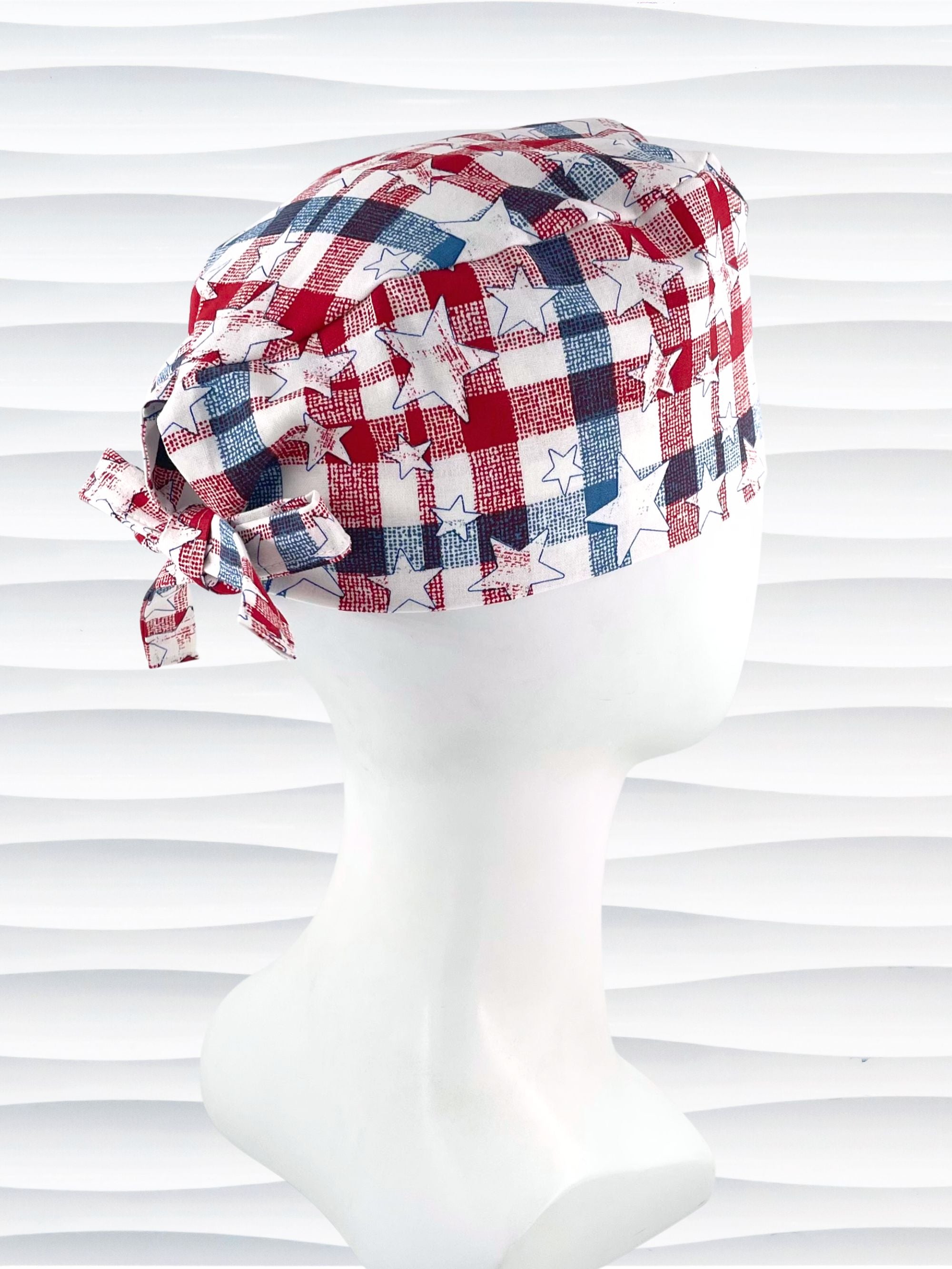 Surgeon style surgical scrub cap with a red and blue plaid print with white stars on cotton fabric.