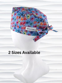 Surgeon style surgical scrub cap by JensCaps with red, blue, yellow, and green fireworks that look like flowers all over a medium blue background on cotton fabric.