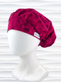 Bouffant style surgical scrub cap with a muted pattern of black circles and lines on deep red or magenta cotton fabric.