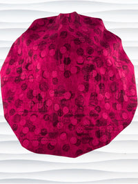 Bouffant style surgical scrub cap with a muted pattern of black circles and lines on deep red or magenta cotton fabric.
