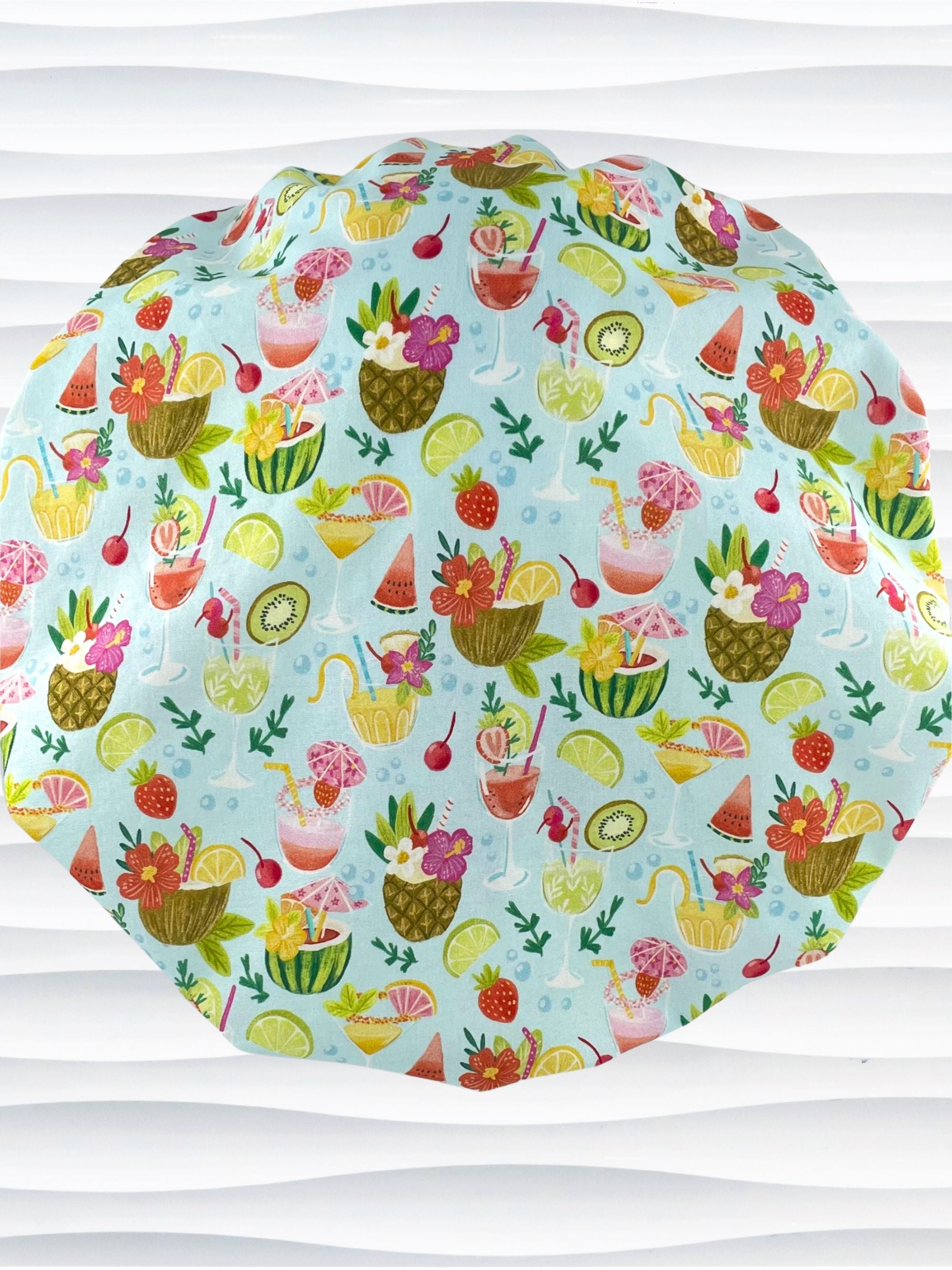 Bouffant surgical scrub cap by JensCaps with iconic tropical drinks with umbrellas and flowers in pinks and yellows and greens on light blue cotton fabric.