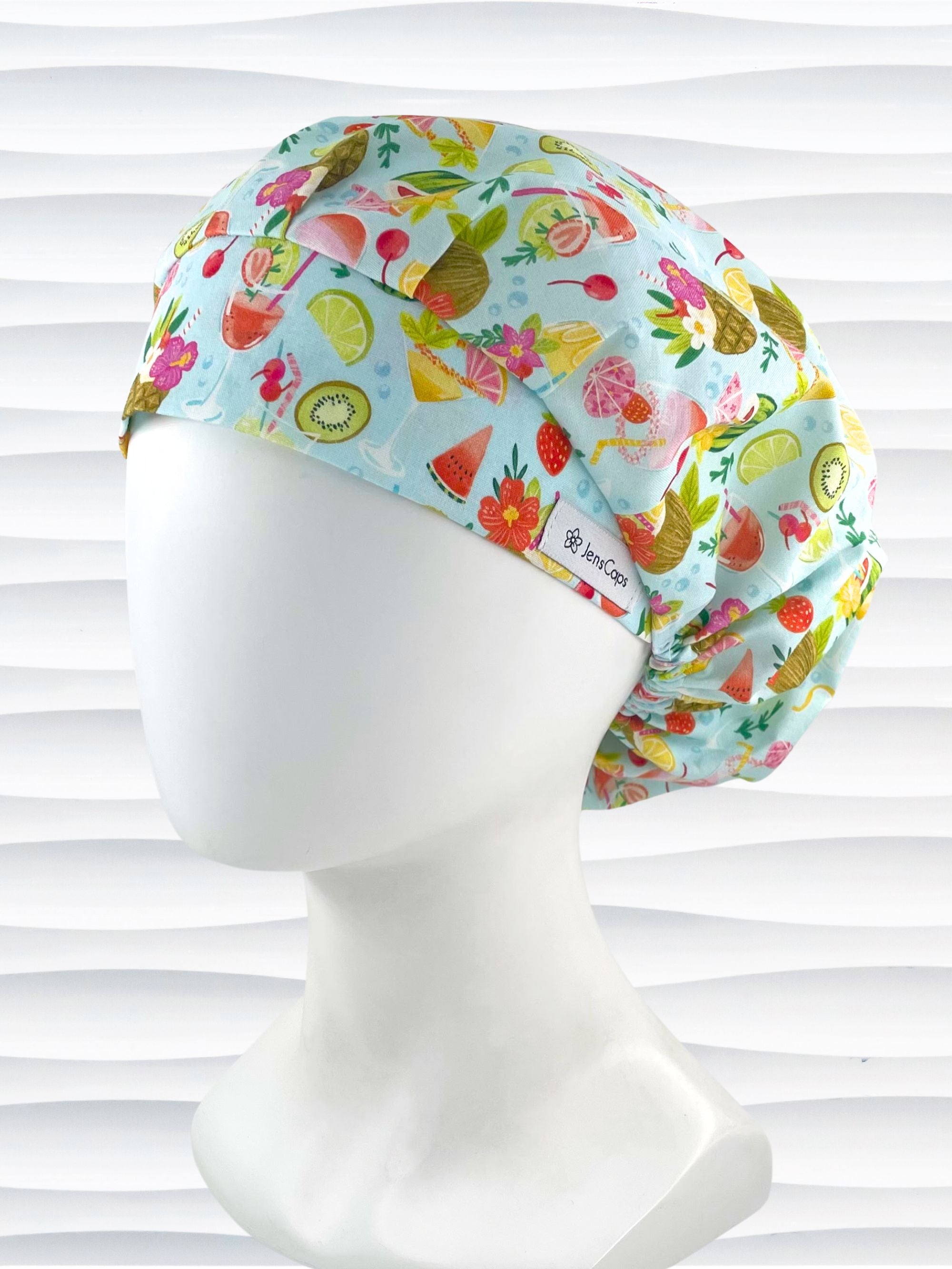 Bouffant surgical scrub cap by JensCaps with iconic tropical drinks with umbrellas and flowers in pinks and yellows and greens on light blue cotton fabric.
