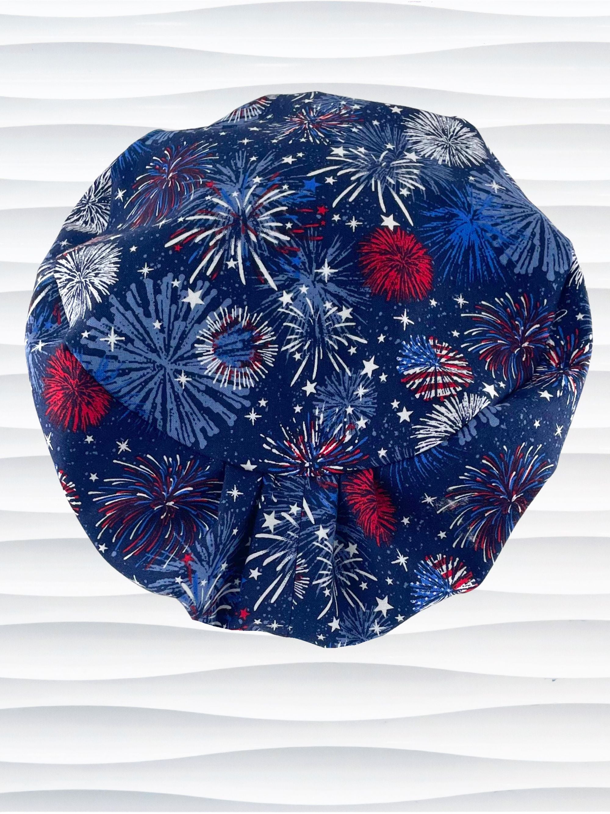 Euro Pixie style surgical scrub cap by JensCaps with fireworks and stars in red white and blue all over navy blue cotton fabric.