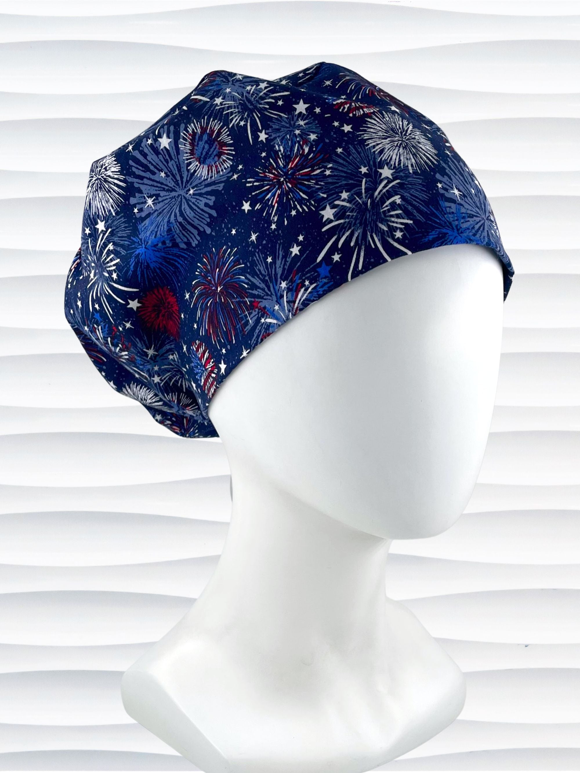 Euro Pixie style surgical scrub cap by JensCaps with fireworks and stars in red white and blue all over navy blue cotton fabric.