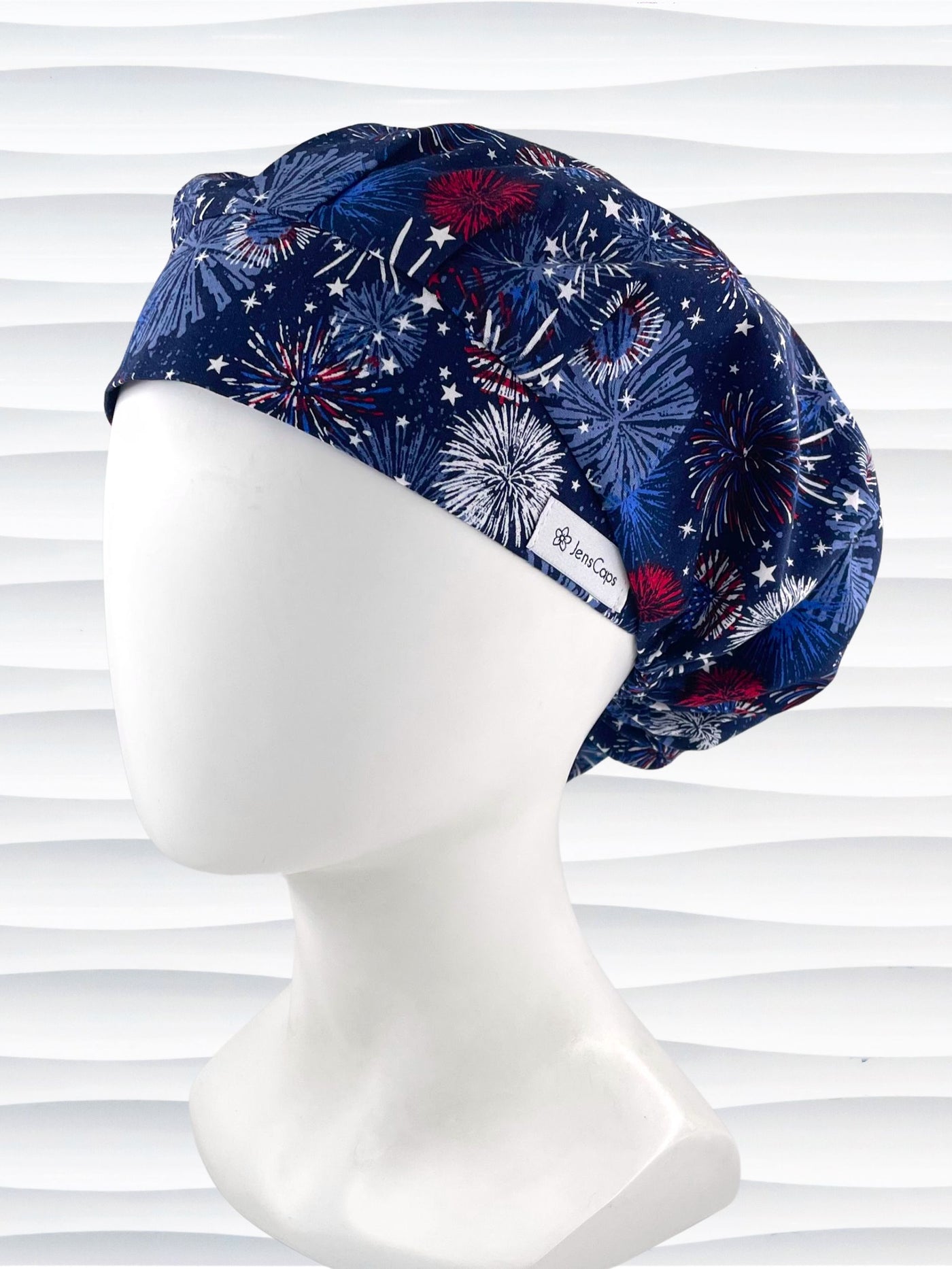 Bouffant style surgical scrub cap by JensCaps with fireworks and stars in red white and blue all over navy blue cotton fabric.
