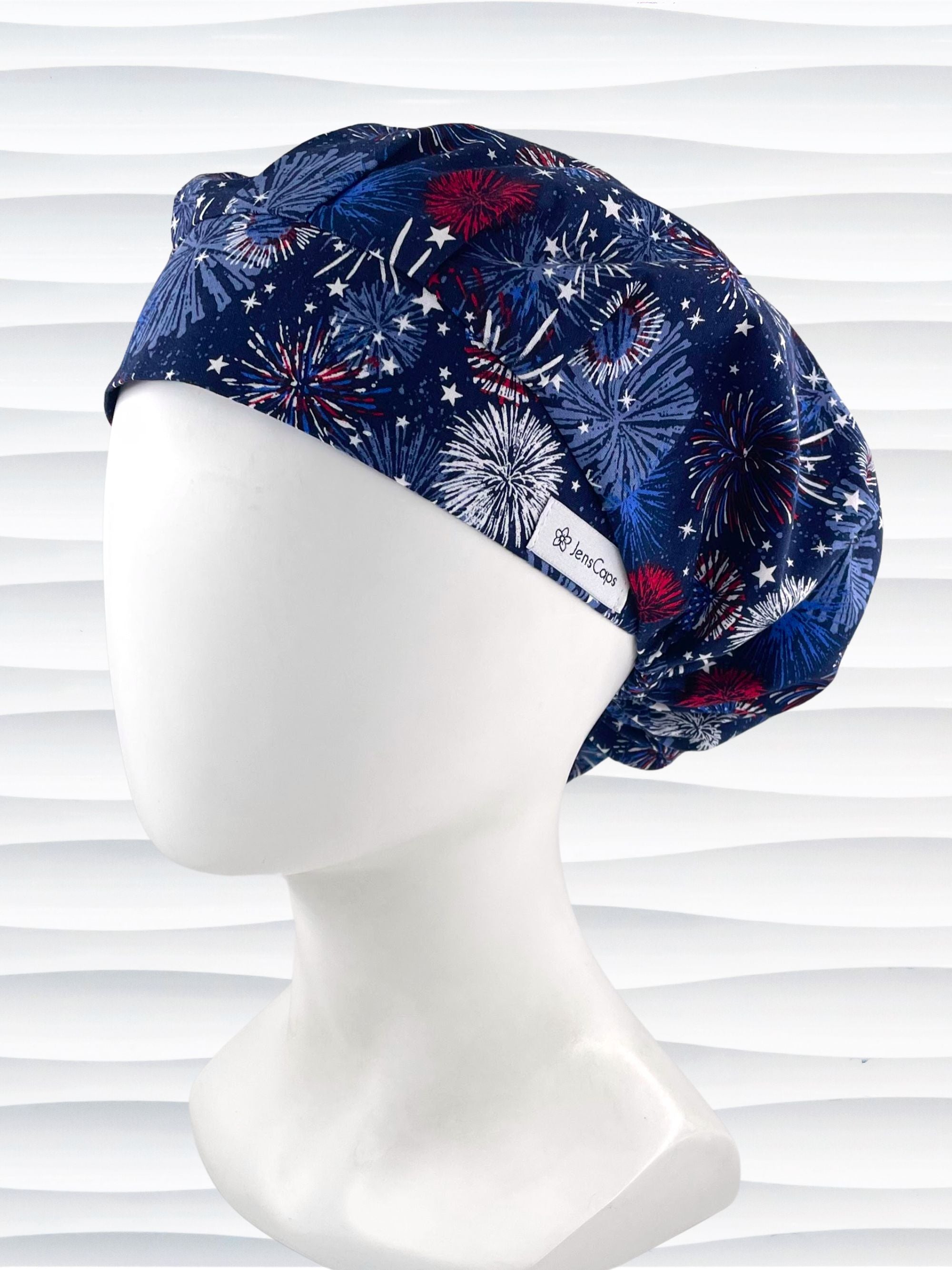 Bouffant style surgical scrub cap by JensCaps with fireworks and stars in red white and blue all over navy blue cotton fabric.