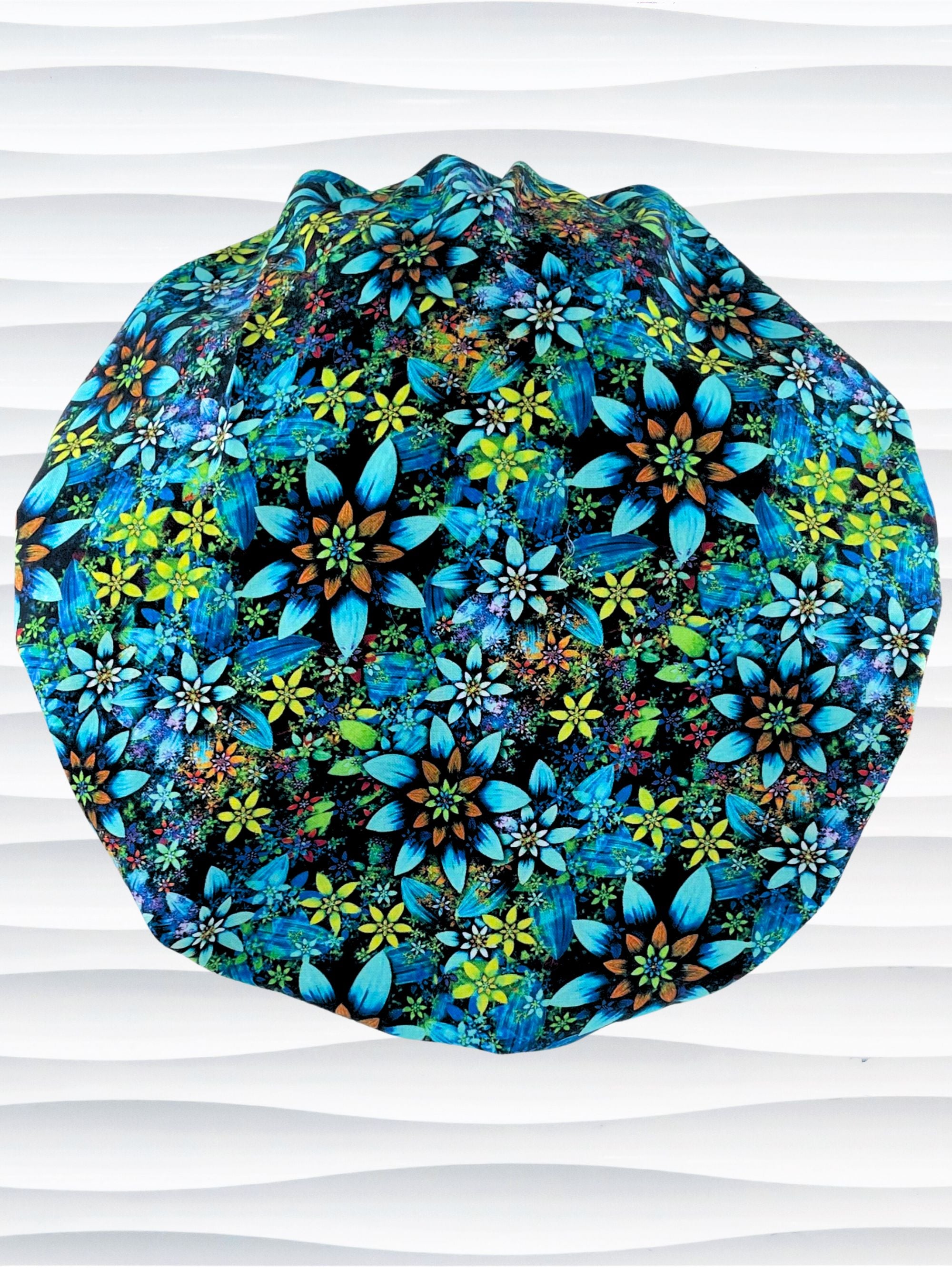 Bouffant style surgical scrub cap with electric bright flowers in green, yellow, white, orange, and blue all over a dark background cotton fabric.