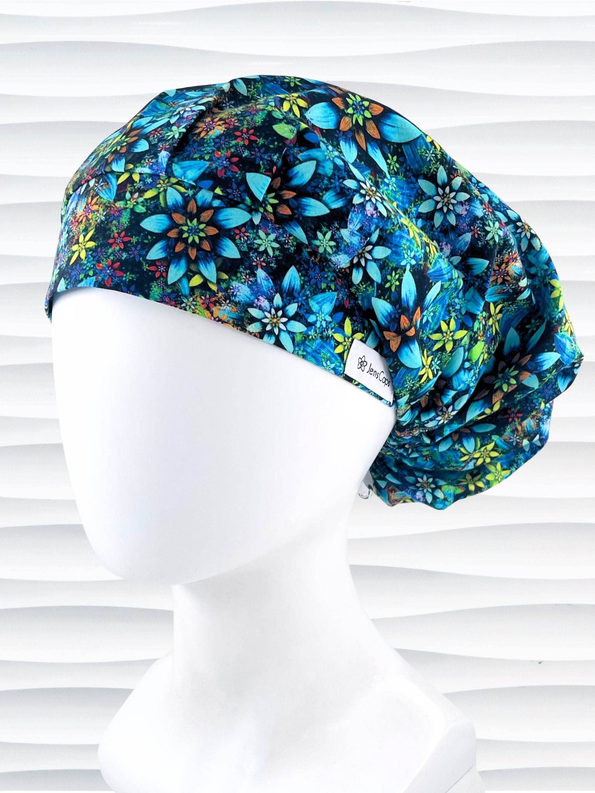 Bouffant style surgical scrub cap with electric bright flowers in green, yellow, white, orange, and blue all over a dark background cotton fabric.