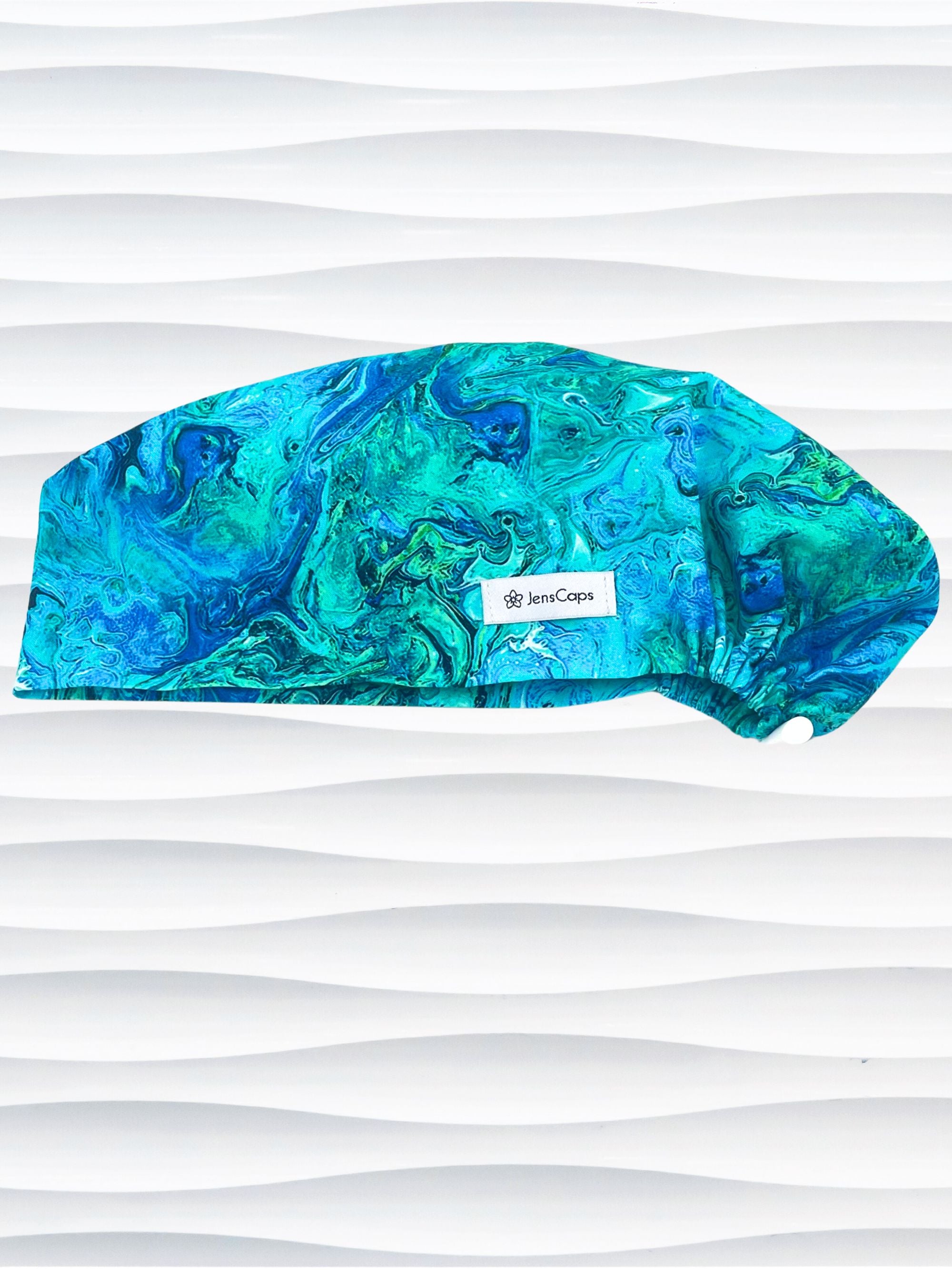 Euro Pixie style surgical scrub cap with a marbled pattern of blues and green that look like ocean tide pools or marbled turquoise on cotton fabric.