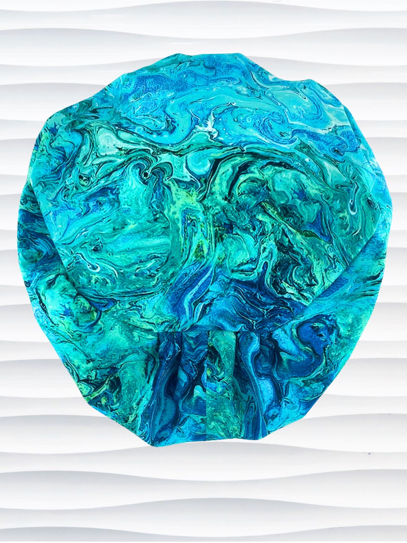 Euro Pixie style surgical scrub cap with a marbled pattern of blues and green that look like ocean tide pools or marbled turquoise on cotton fabric.