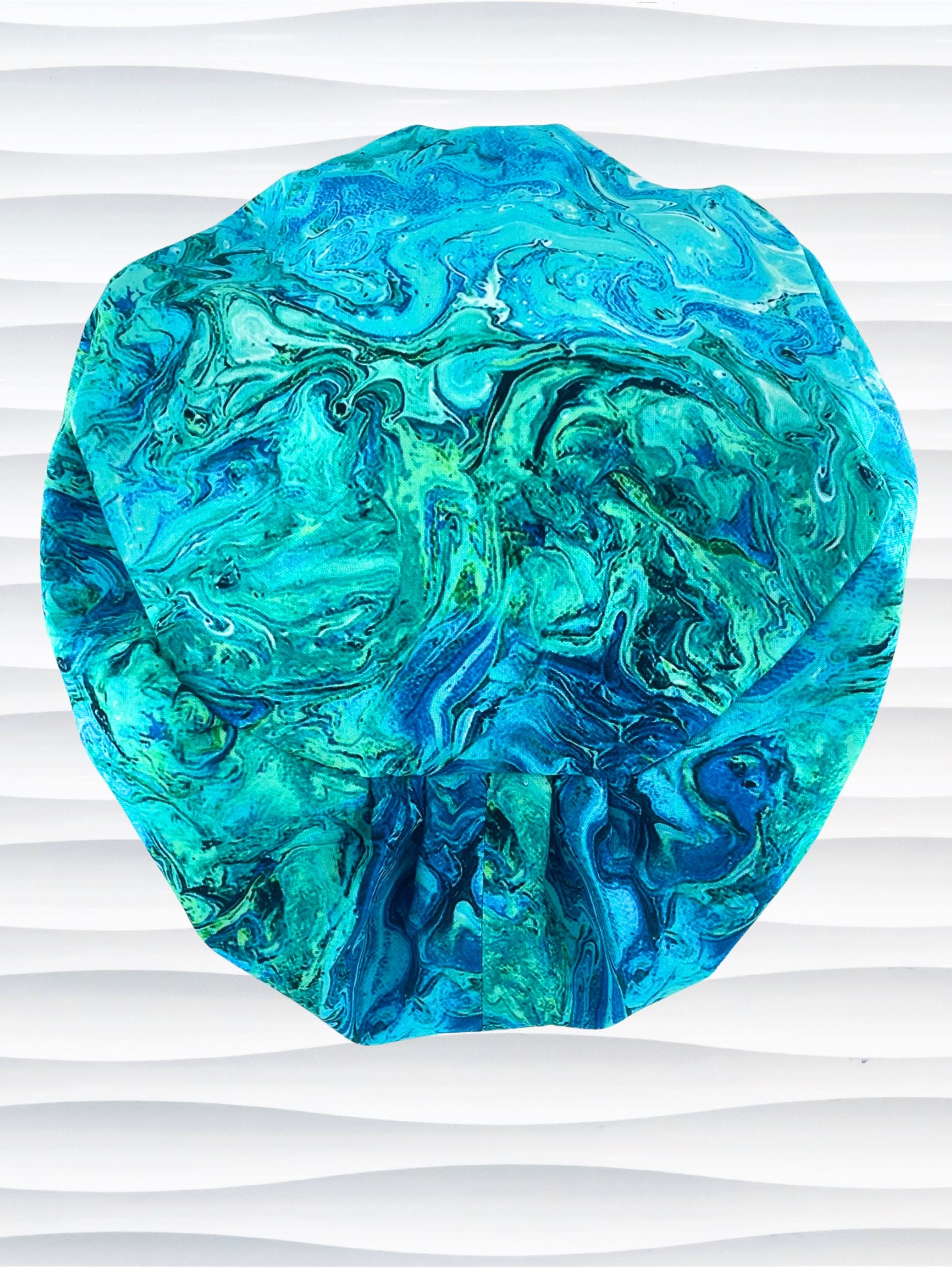 Euro Pixie style surgical scrub cap with a marbled pattern of blues and green that look like ocean tide pools or marbled turquoise on cotton fabric.