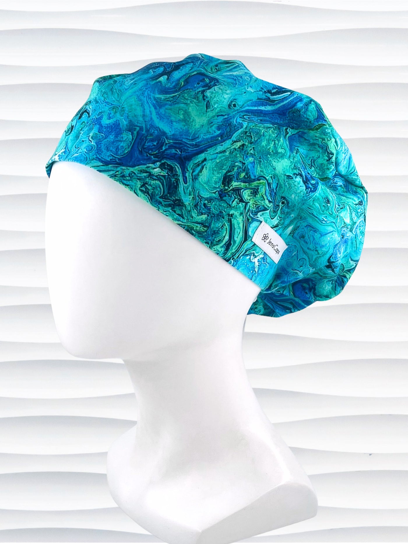 Euro Pixie style surgical scrub cap with a marbled pattern of blues and green that look like ocean tide pools or marbled turquoise on cotton fabric.