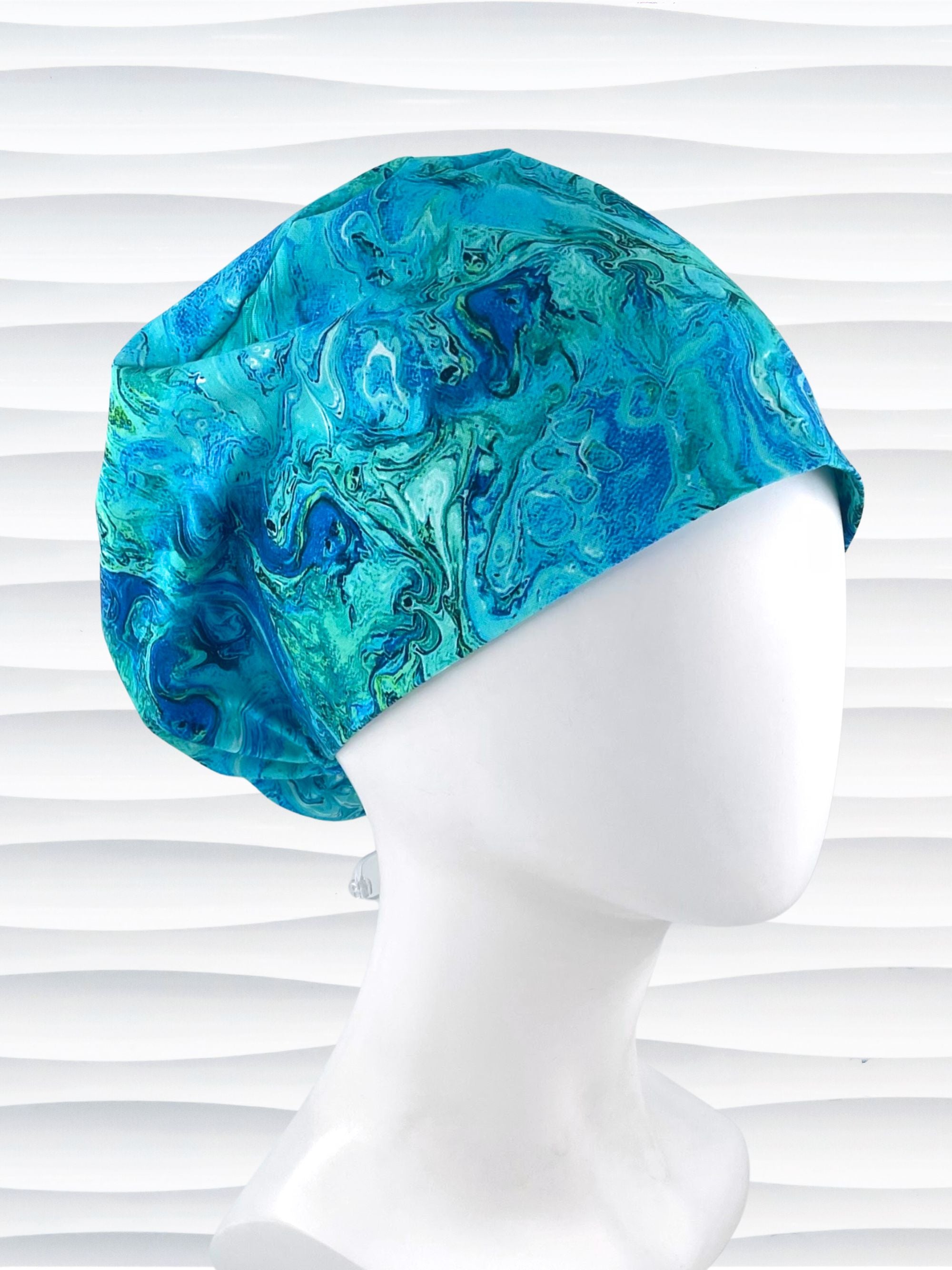 Euro Pixie style surgical scrub cap with a marbled pattern of blues and green that look like ocean tide pools or marbled turquoise on cotton fabric.