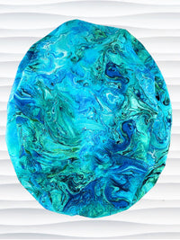 Euro Ponytail surgical scrub cap with a marbled pattern of blues and green that look like ocean tide pools or marbled turquoise on cotton fabric, finished with a tie, and displayed on a white mannequin head.