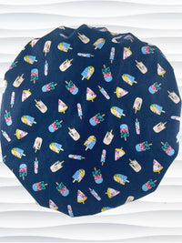 Bouffant style surgical scrub cap backview with popsicles in pink and blue and yellow all over a dark blue cotton fabric.