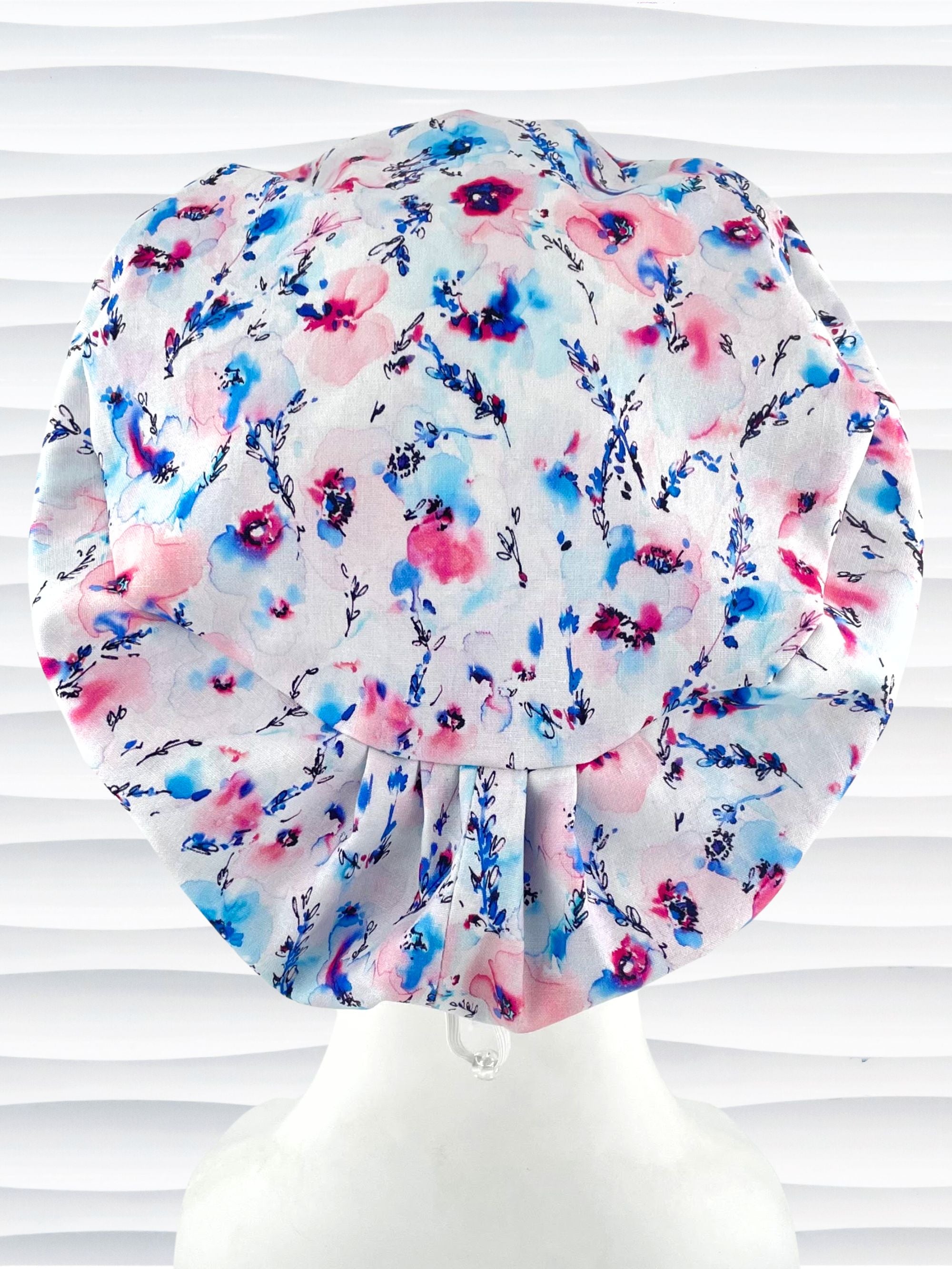 Women's euro pixie scrub cap with watercolor floral print in pink, blue, and purple on a white background, ideal for nurses, doctors, and medical professionals seeking stylish and comfortable headwear