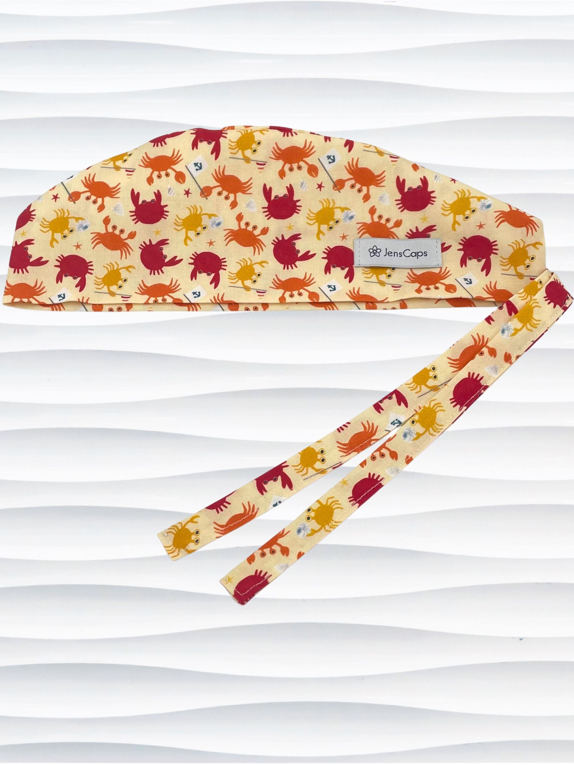 Colorful crab print surgical scrub cap featuring orange, red, and yellow cartoon crabs on cream fabric, displayed on mannequin head – handmade nurse and doctor scrub hat by JensCaps