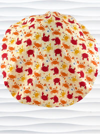 Colorful crab print surgical scrub cap featuring orange, red, and yellow cartoon crabs on cream fabric, displayed on mannequin head – handmade nurse and doctor scrub hat by JensCaps