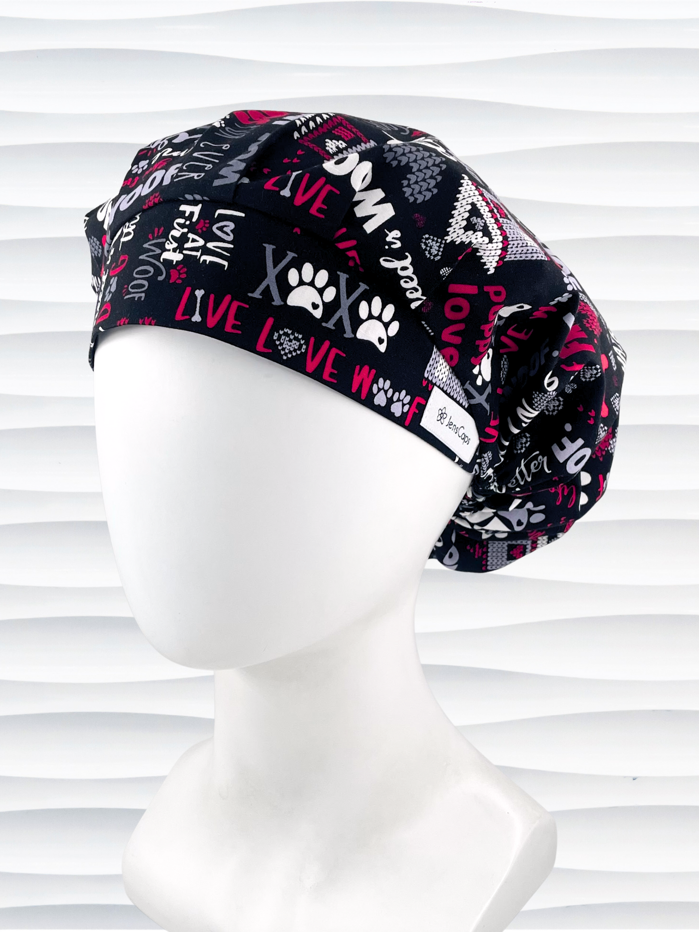 Bouffant style scrub cap by JensCaps with dog paws, bones,hearts, and sayings about puppies in red, gray, and white on black cotton fabric.