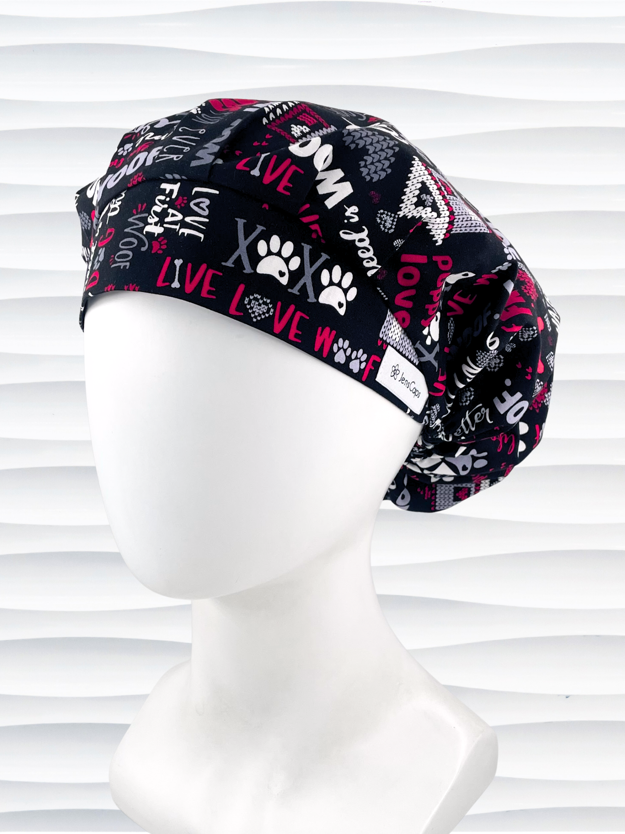 Bouffant style scrub cap by JensCaps with dog paws, bones,hearts, and sayings about puppies in red, gray, and white on black cotton fabric.