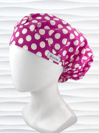 Bouffant style surgical scrub cap by JensCaps with large white dots on raspberry colored cotton fabric.