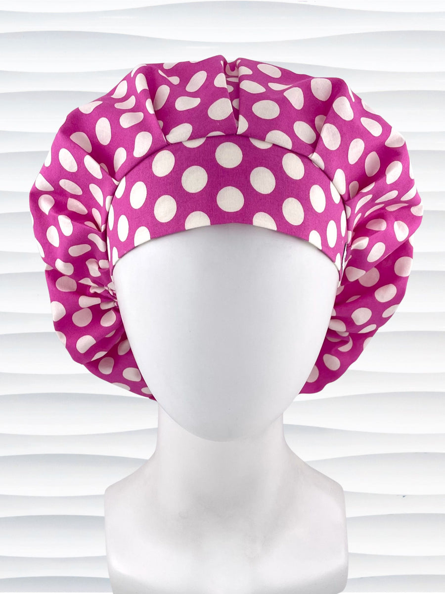 Bouffant style surgical scrub cap by JensCaps with large white dots on raspberry colored cotton fabric.