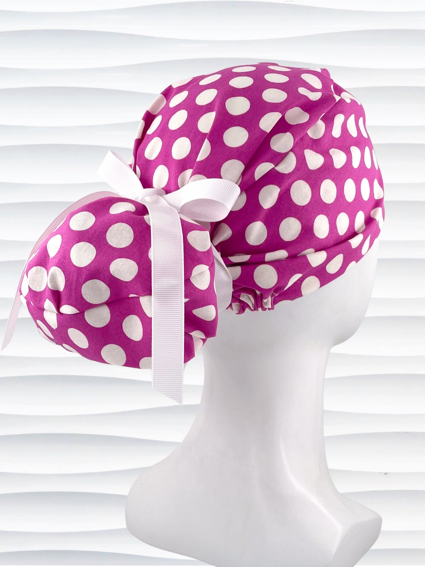 Euro Pony style ponytail surgical scrub cap by JensCaps with large white dots on raspberry colored cotton fabric.