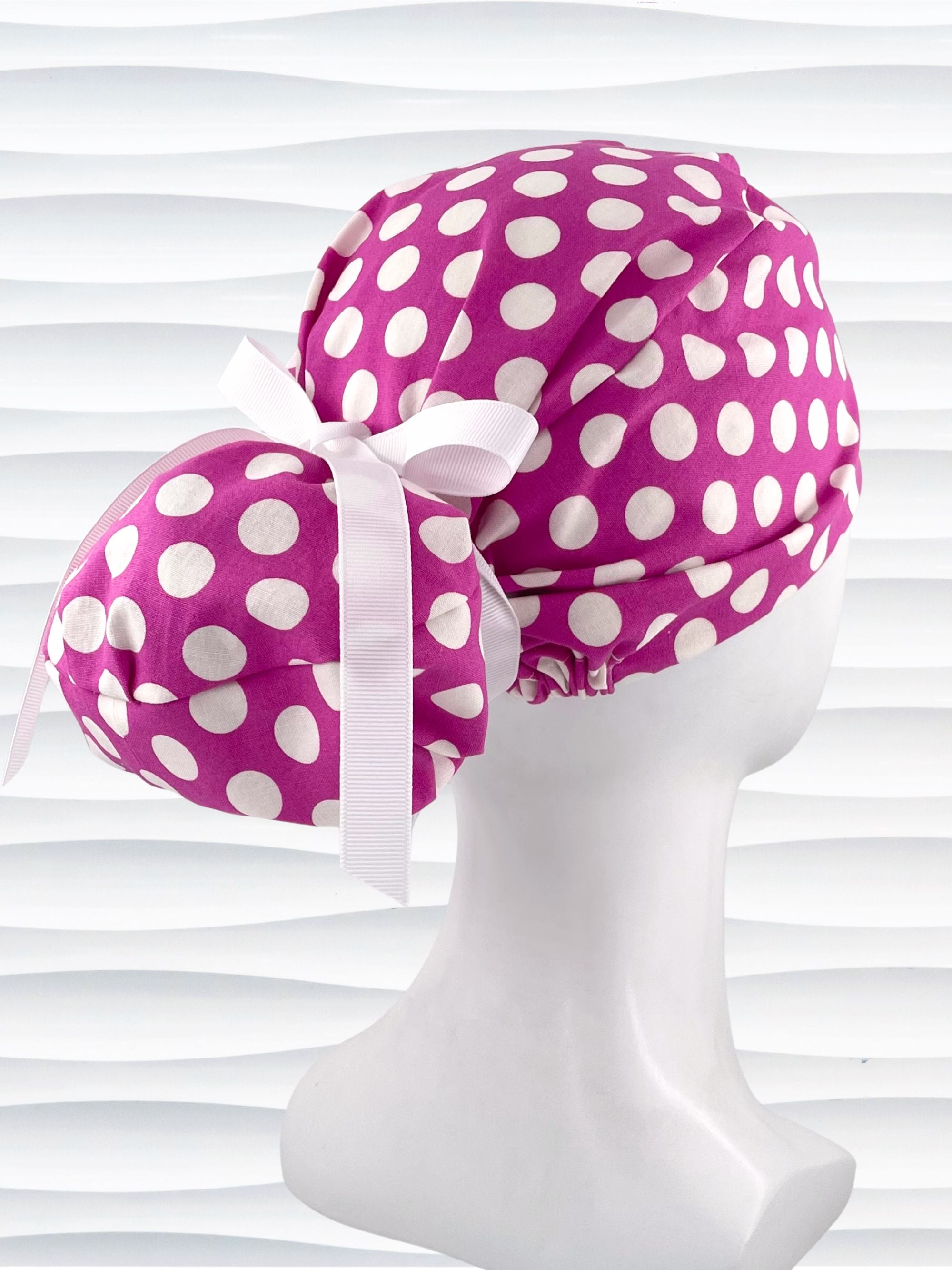 Euro Pony style ponytail surgical scrub cap by JensCaps with large white dots on raspberry colored cotton fabric.