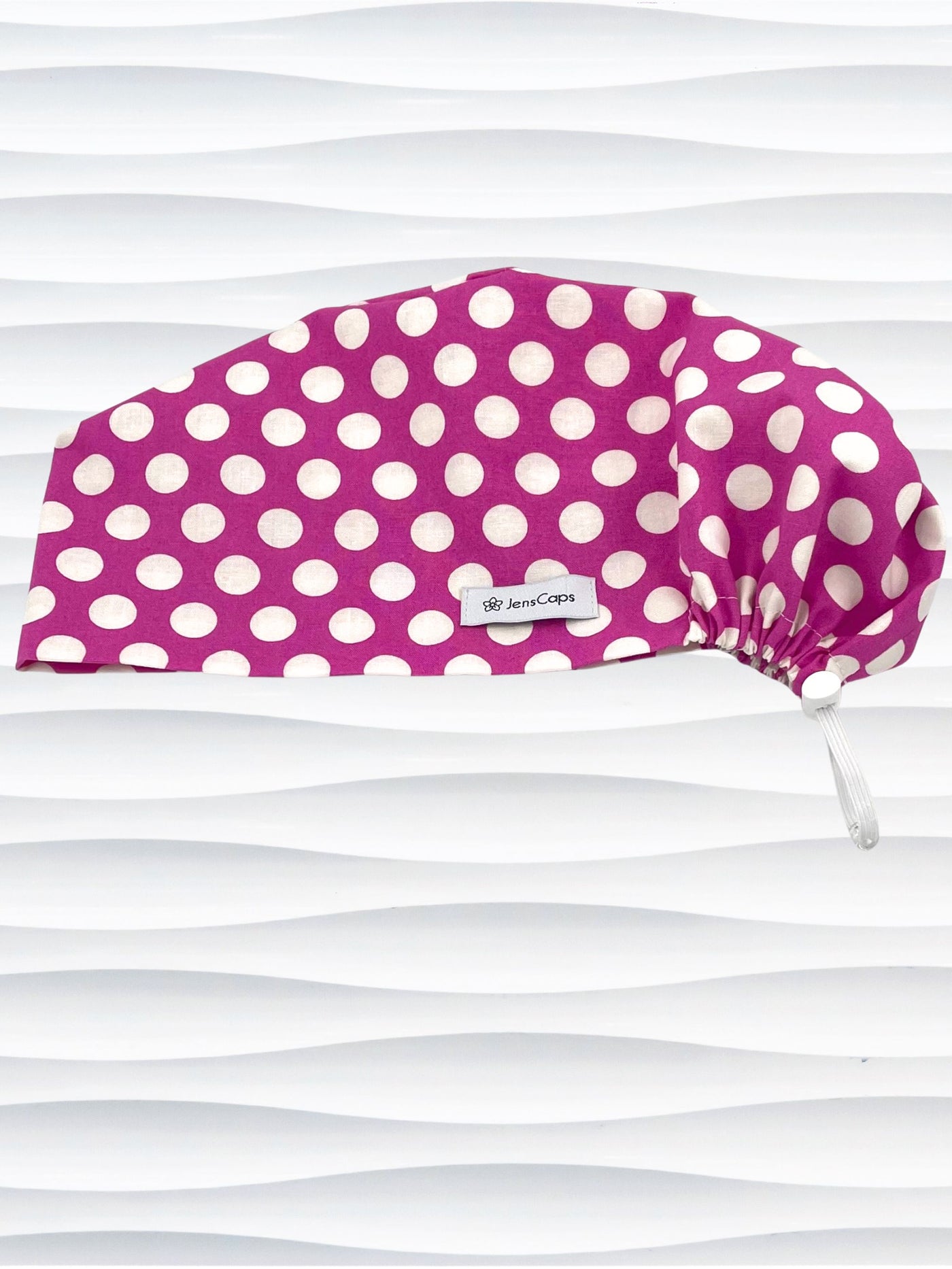 Euro Pixie style surgical scrub cap with large white dots on raspberry colored cotton fabric.