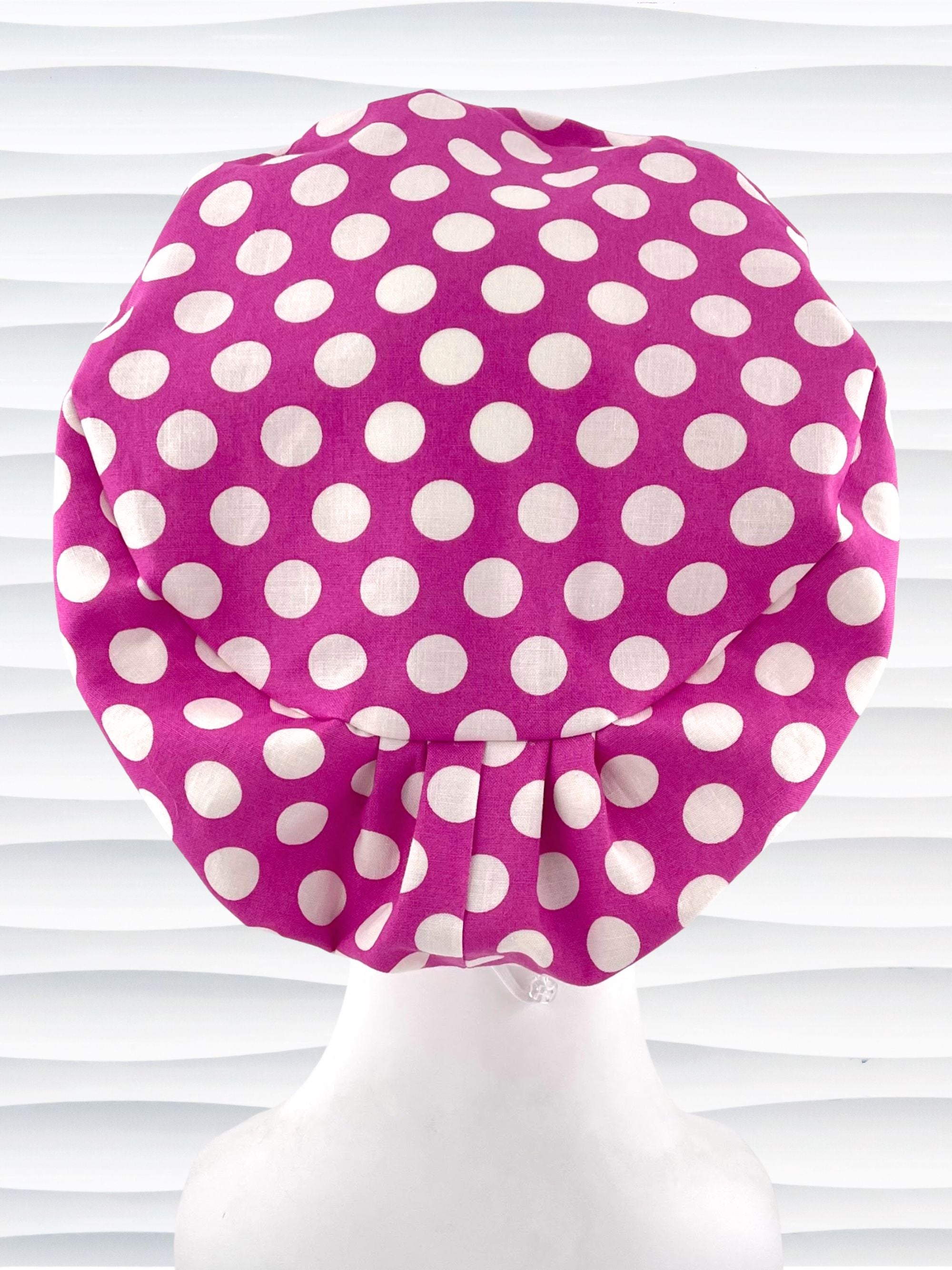 Euro Pixie style surgical scrub cap with large white dots on raspberry colored cotton fabric.