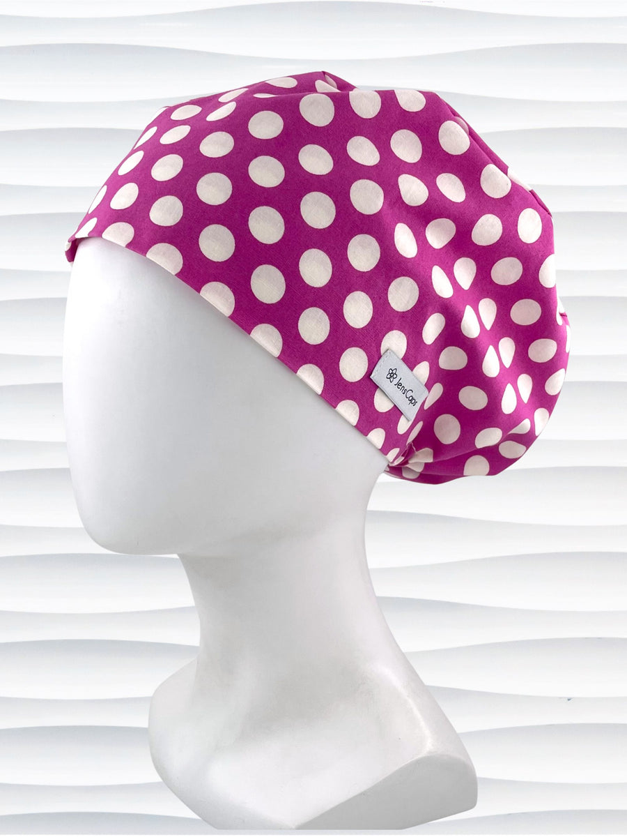 Euro Pixie style surgical scrub cap with large white dots on raspberry colored cotton fabric.