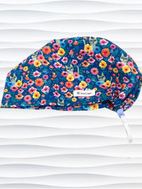Euro Pixie style surgical scrub cap by JensCaps with gray cats hiding in a garden of yellow, pink, and red flowers on a dark blue cotton fabric