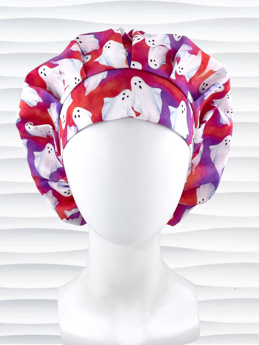 Bouffant style surgical scrub cap by JensCaps with white sheet ghosts tossed all aver an ombre red and purple cotton fabric.